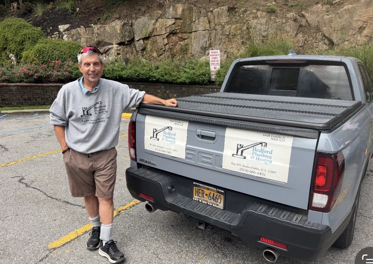 Joseph Casarella, Jr. standing beside his Bedford Plumbing & Heating pickup truck